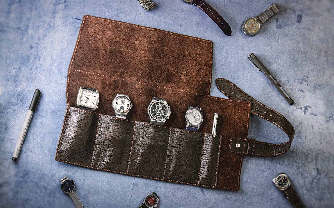 A collection of vintage watches in a handmade leather roll case, perfect for travel.